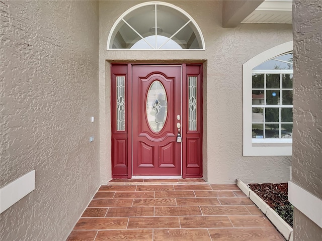 entrance to property featuring stucco siding and a baseboard radiator