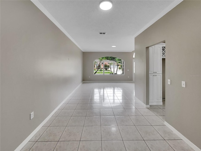 spare room with light tile patterned floors, baseboards, visible vents, and ornamental molding