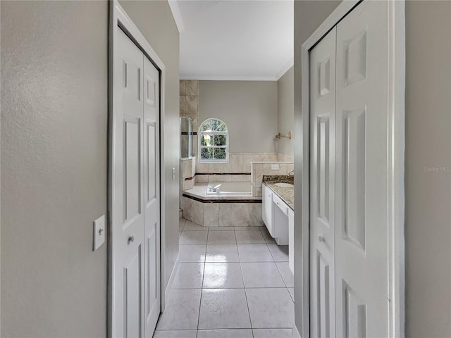 bathroom with tile patterned flooring, tiled bath, vanity, and crown molding