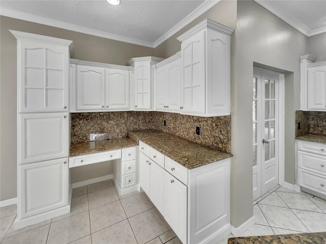 kitchen featuring a textured ceiling, light tile patterned floors, backsplash, white cabinets, and dark stone counters