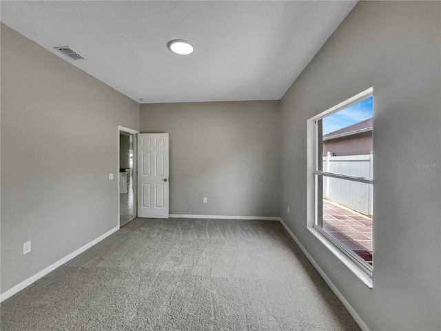 carpeted spare room with visible vents, baseboards, and a wealth of natural light