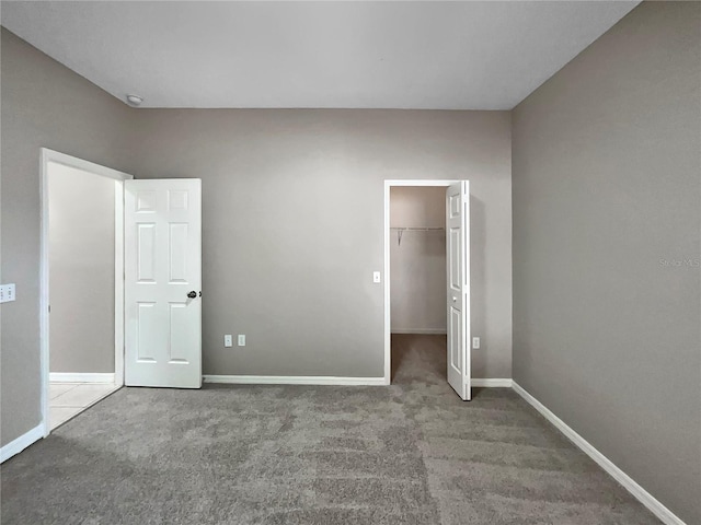 unfurnished bedroom with a walk in closet, carpet flooring, and a closet