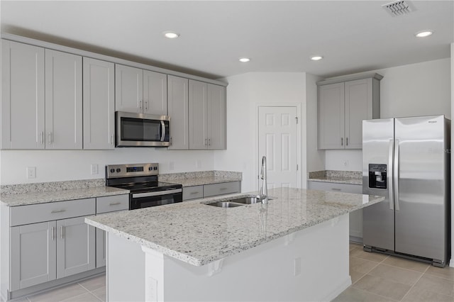 kitchen featuring stainless steel appliances, a kitchen island with sink, sink, and light tile patterned floors