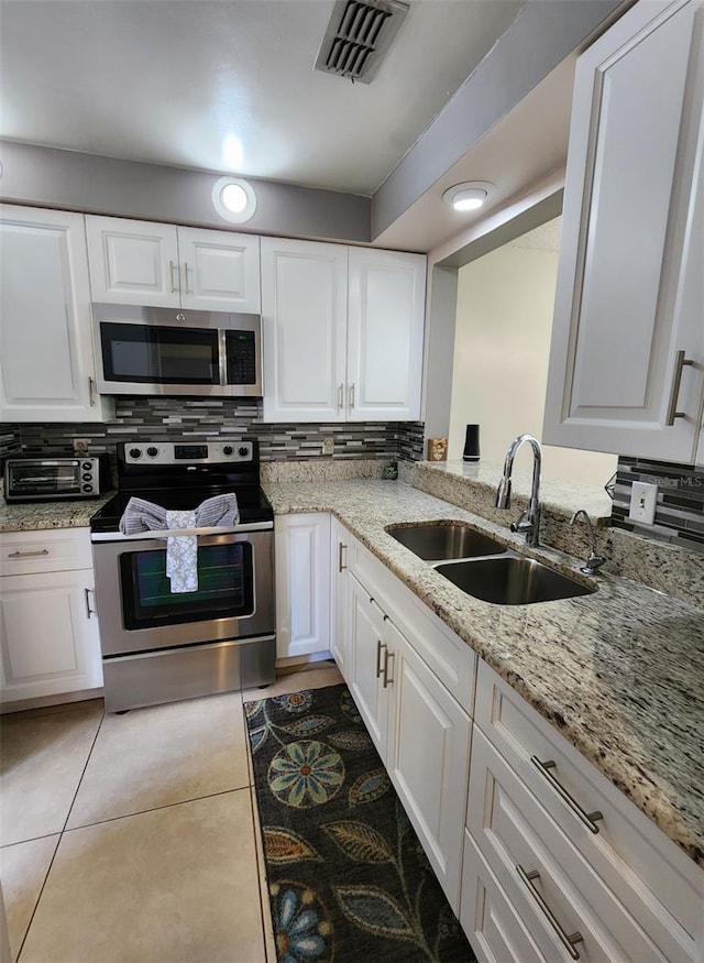 kitchen featuring appliances with stainless steel finishes, white cabinetry, and sink