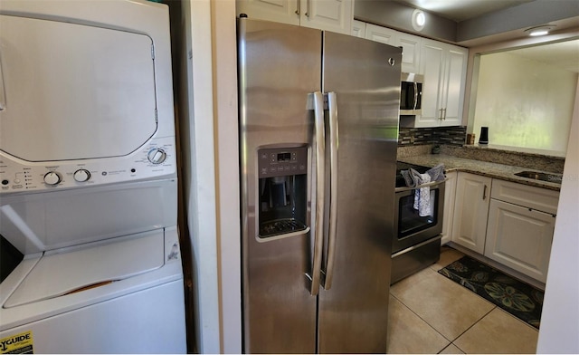 clothes washing area featuring light tile patterned floors and stacked washer and dryer