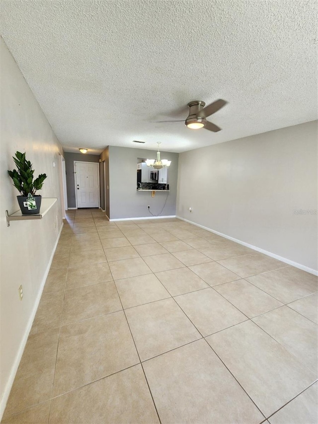 unfurnished living room with ceiling fan with notable chandelier, light tile patterned floors, and a textured ceiling