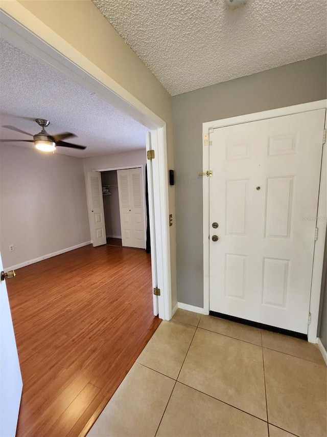 foyer with a textured ceiling, ceiling fan, and wood-type flooring