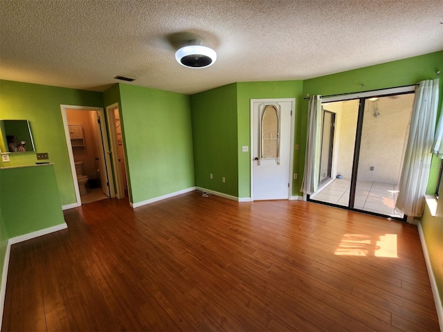 unfurnished bedroom featuring ensuite bath, a textured ceiling, and hardwood / wood-style flooring