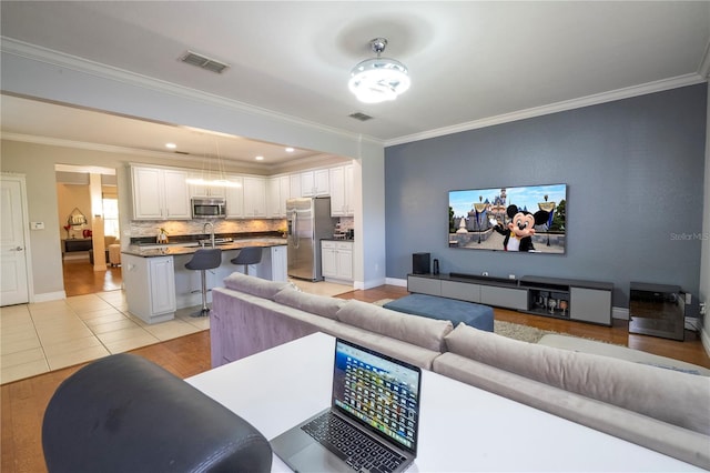 living room featuring crown molding, ceiling fan, sink, and light tile patterned floors