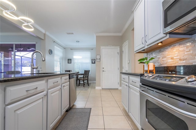 kitchen with white cabinets, ornamental molding, light tile patterned floors, tasteful backsplash, and stainless steel appliances