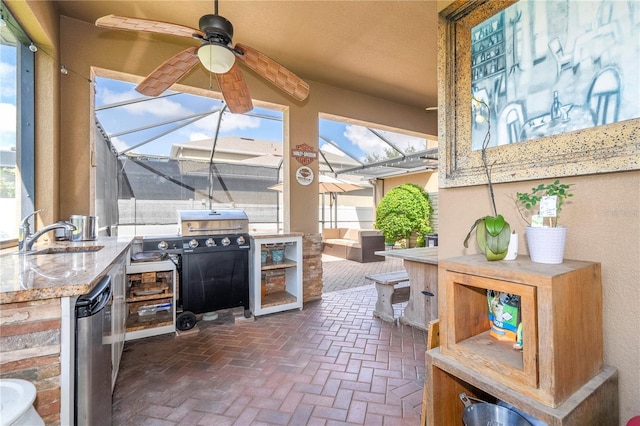 view of patio / terrace featuring an outdoor kitchen, glass enclosure, ceiling fan, and sink