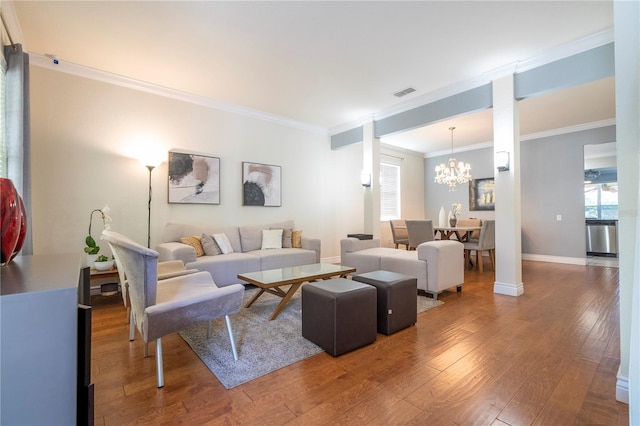 living room featuring wood-type flooring, crown molding, and a chandelier