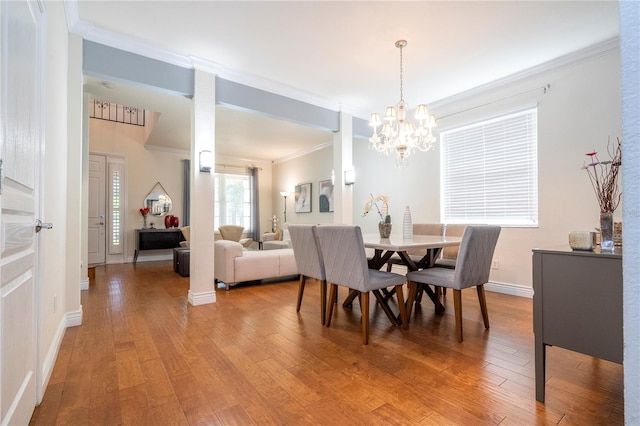 dining room with an inviting chandelier, ornamental molding, and hardwood / wood-style flooring