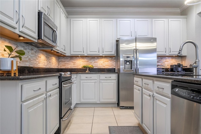 kitchen with stainless steel appliances, light tile patterned flooring, tasteful backsplash, and white cabinetry