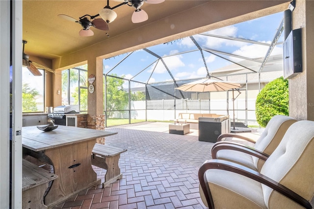 view of patio featuring glass enclosure, area for grilling, and ceiling fan