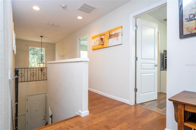 corridor featuring light hardwood / wood-style floors and an inviting chandelier