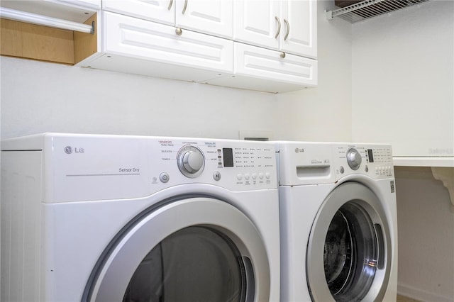 laundry area with washing machine and clothes dryer and cabinets