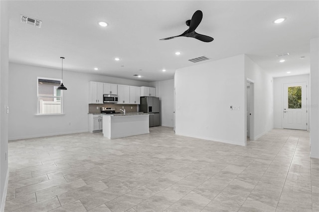 kitchen featuring plenty of natural light, ceiling fan, appliances with stainless steel finishes, and a kitchen island with sink