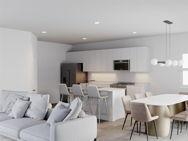 interior space featuring pendant lighting, stainless steel fridge, sink, a breakfast bar, and white cabinets