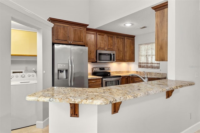 kitchen with washer / dryer, kitchen peninsula, and a kitchen breakfast bar