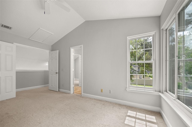 empty room featuring lofted ceiling, ceiling fan, a wealth of natural light, and light carpet