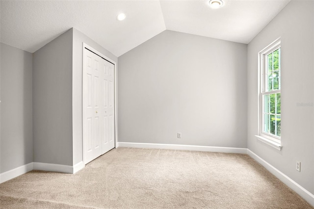 unfurnished bedroom with lofted ceiling, carpet, and a closet