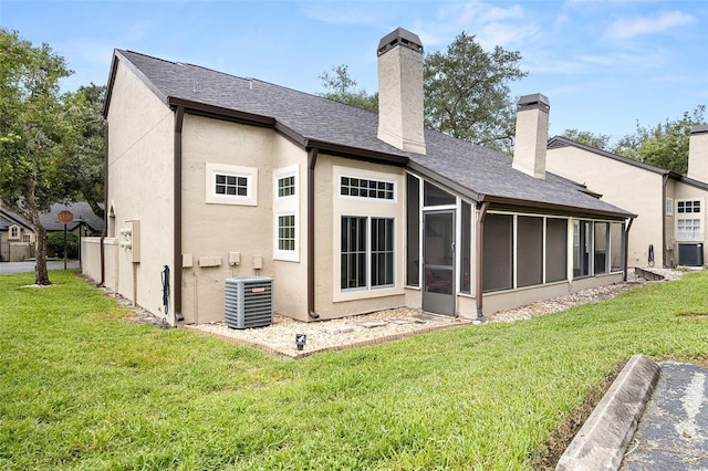 rear view of house featuring central AC unit, a sunroom, and a lawn