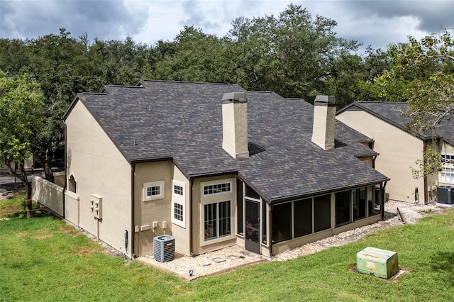 rear view of property featuring a yard, a sunroom, and central AC