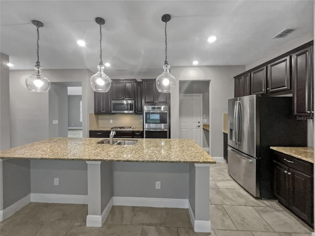 kitchen with dark brown cabinetry, appliances with stainless steel finishes, hanging light fixtures, and a kitchen island with sink