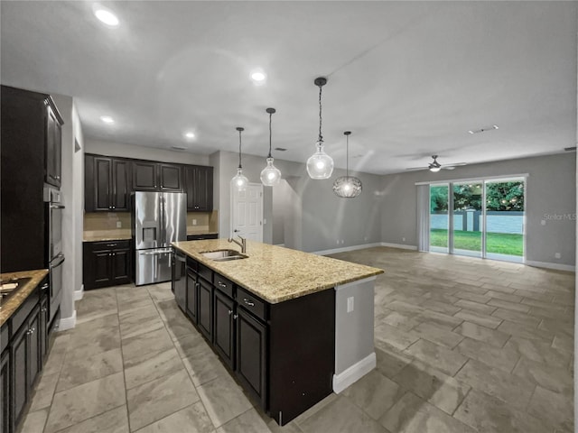 kitchen with pendant lighting, stainless steel appliances, an island with sink, ceiling fan, and sink