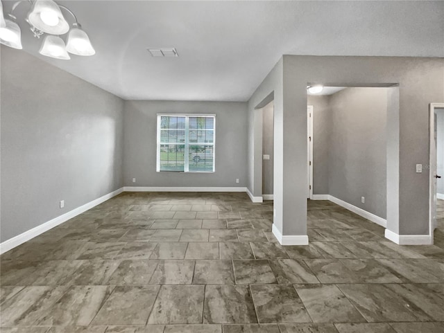 unfurnished room featuring a chandelier