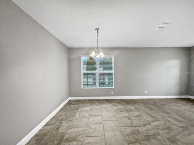 spare room featuring an inviting chandelier