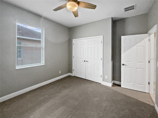 unfurnished bedroom with a closet, ceiling fan, and dark colored carpet