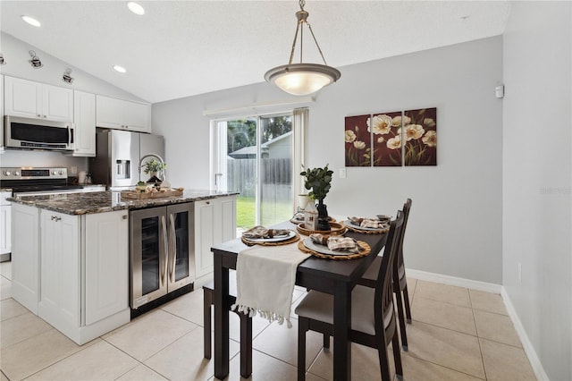 kitchen with decorative light fixtures, white cabinetry, beverage cooler, dark stone counters, and stainless steel appliances