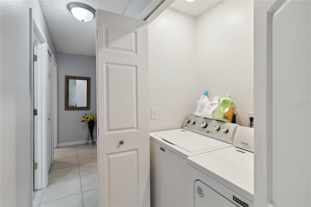 clothes washing area with separate washer and dryer, light tile patterned floors, and a textured ceiling