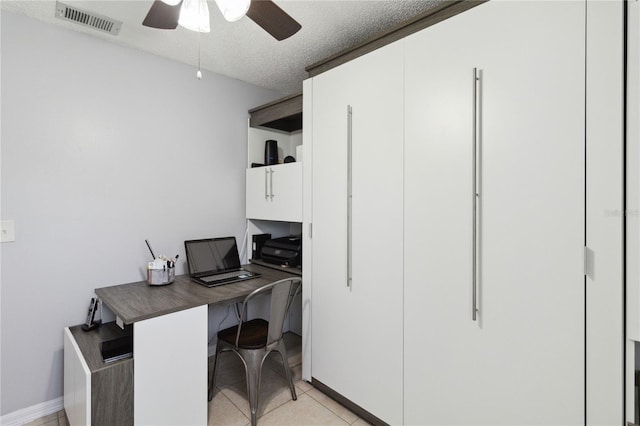 tiled home office with ceiling fan and a textured ceiling