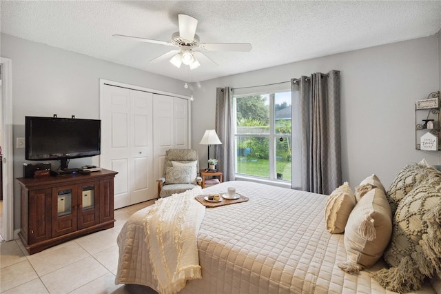 bedroom featuring light tile patterned floors, a textured ceiling, ceiling fan, and a closet