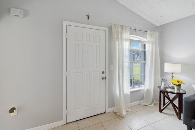 tiled entrance foyer featuring lofted ceiling and a textured ceiling