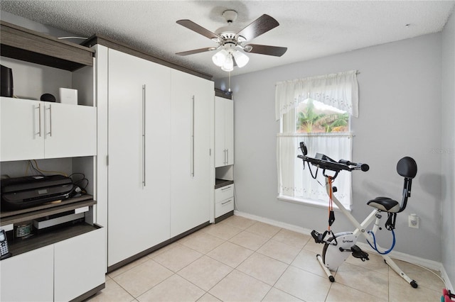 workout room with ceiling fan, a textured ceiling, and light tile patterned floors