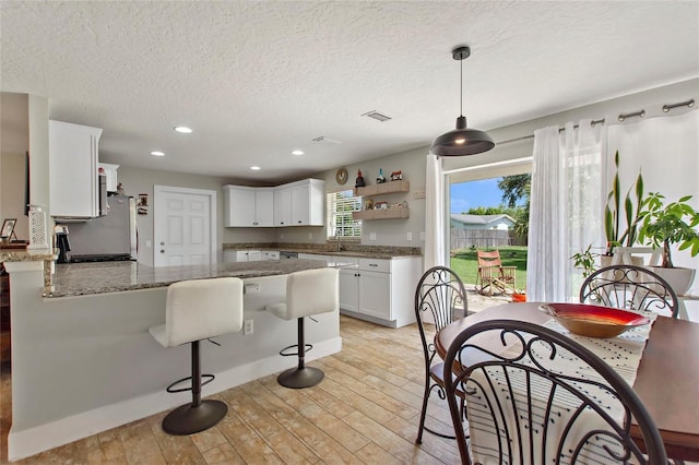 kitchen with white cabinets, open shelves, light wood-style floors, a peninsula, and visible vents