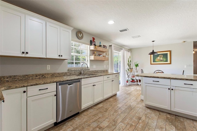 kitchen featuring a sink, dishwasher, a textured ceiling, white cabinetry, and visible vents