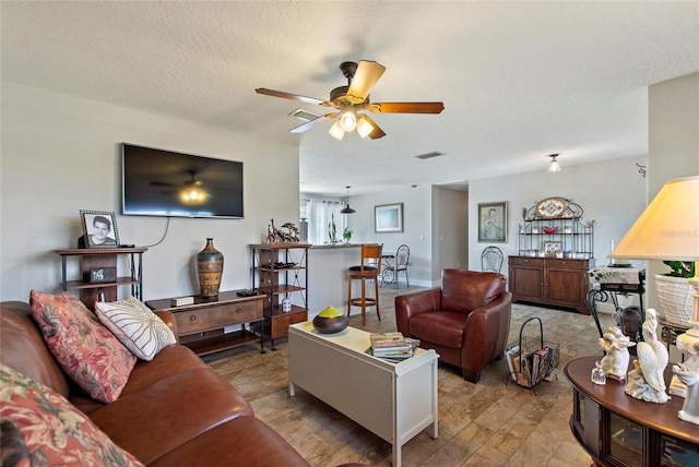 living room featuring ceiling fan, a textured ceiling, and visible vents