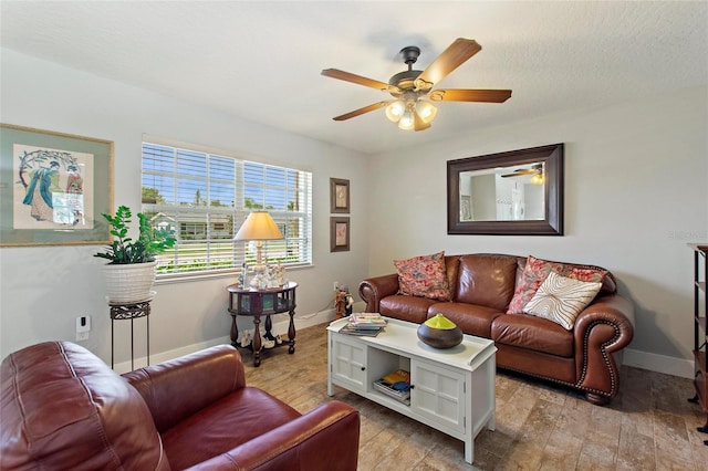 living room featuring baseboards, ceiling fan, and light wood-type flooring