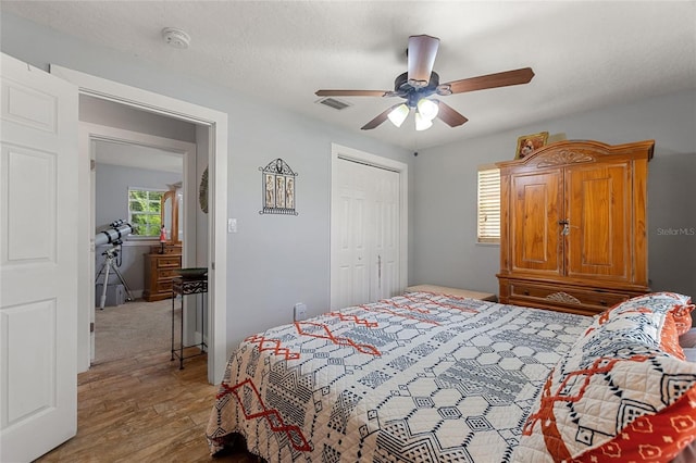bedroom with visible vents, ceiling fan, wood finished floors, and a closet