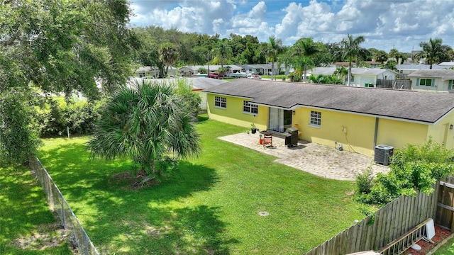 rear view of property featuring a residential view, a patio, a shingled roof, and a lawn