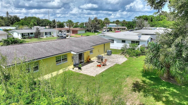 rear view of property featuring stucco siding, central AC unit, a patio area, a lawn, and a residential view
