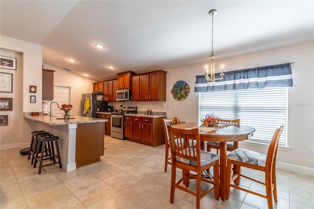 kitchen featuring pendant lighting, vaulted ceiling, kitchen peninsula, appliances with stainless steel finishes, and light stone countertops