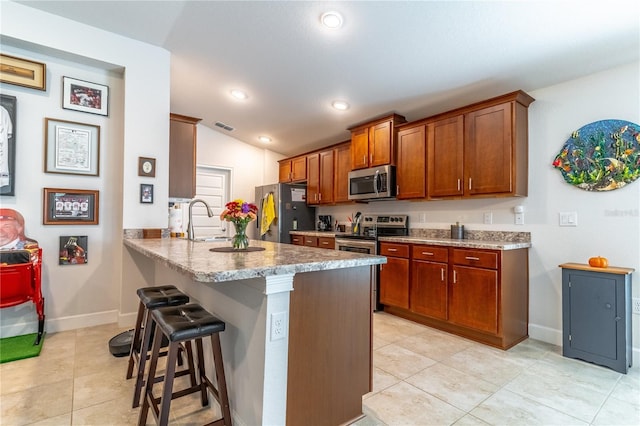 kitchen featuring appliances with stainless steel finishes, vaulted ceiling, a breakfast bar, kitchen peninsula, and sink