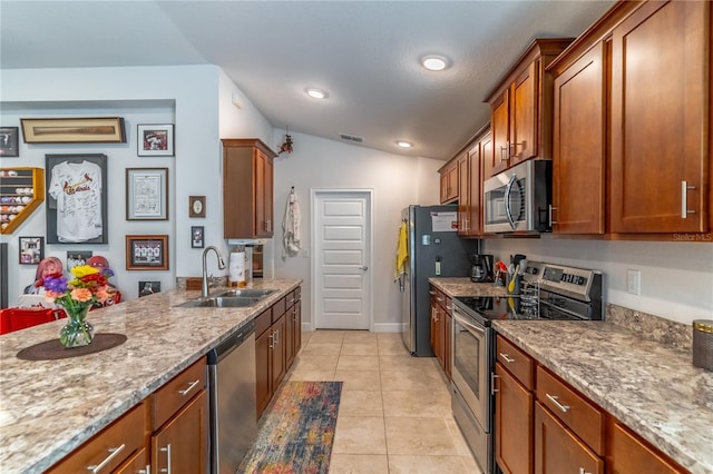 kitchen with light tile patterned floors, sink, stainless steel appliances, light stone countertops, and vaulted ceiling