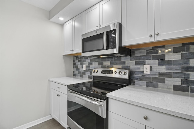 kitchen with light stone counters, white cabinets, stainless steel appliances, and decorative backsplash